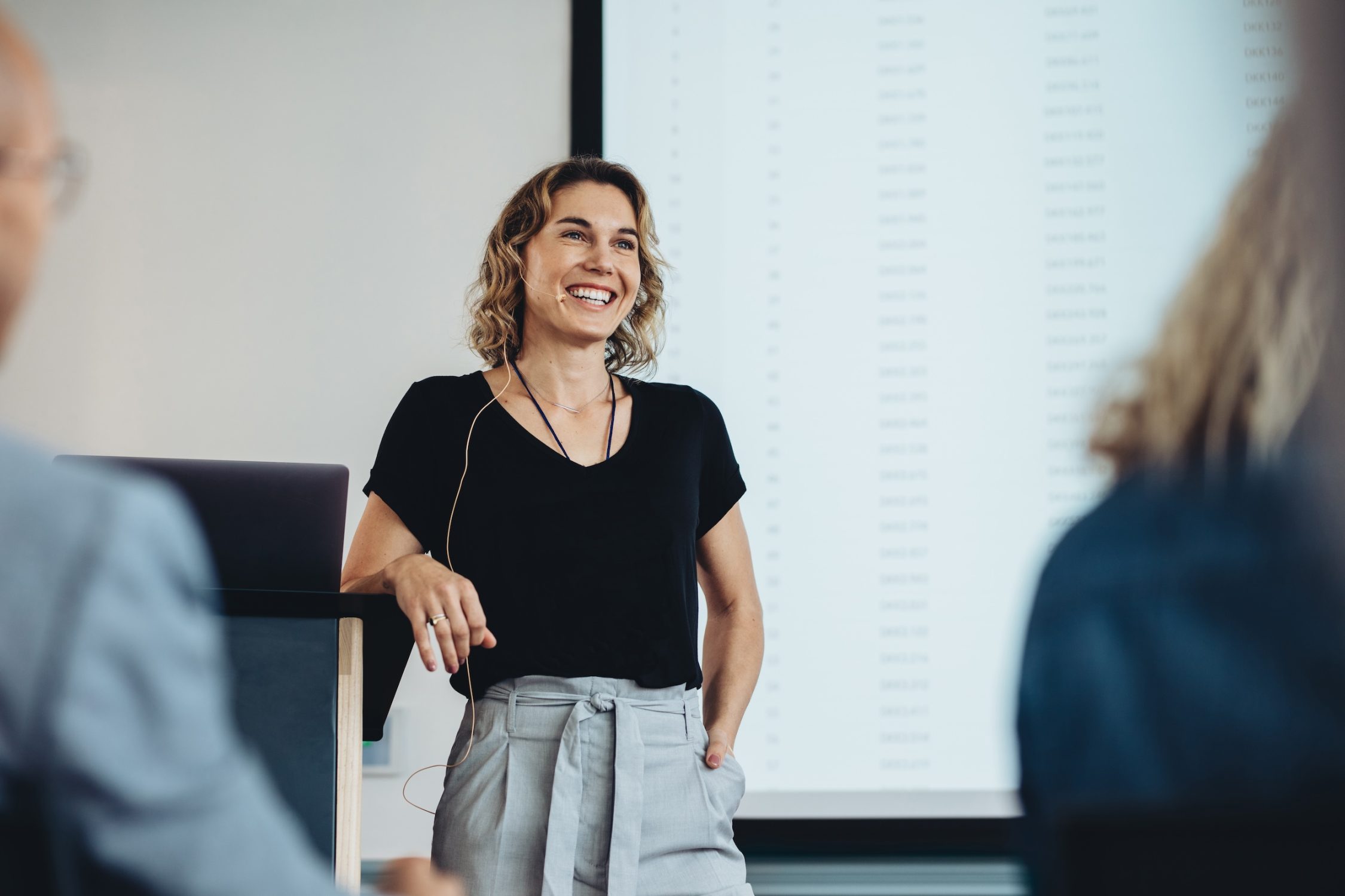 Smiling businesswoman delivering a speech during a conference. Successful business professional giving presentation.