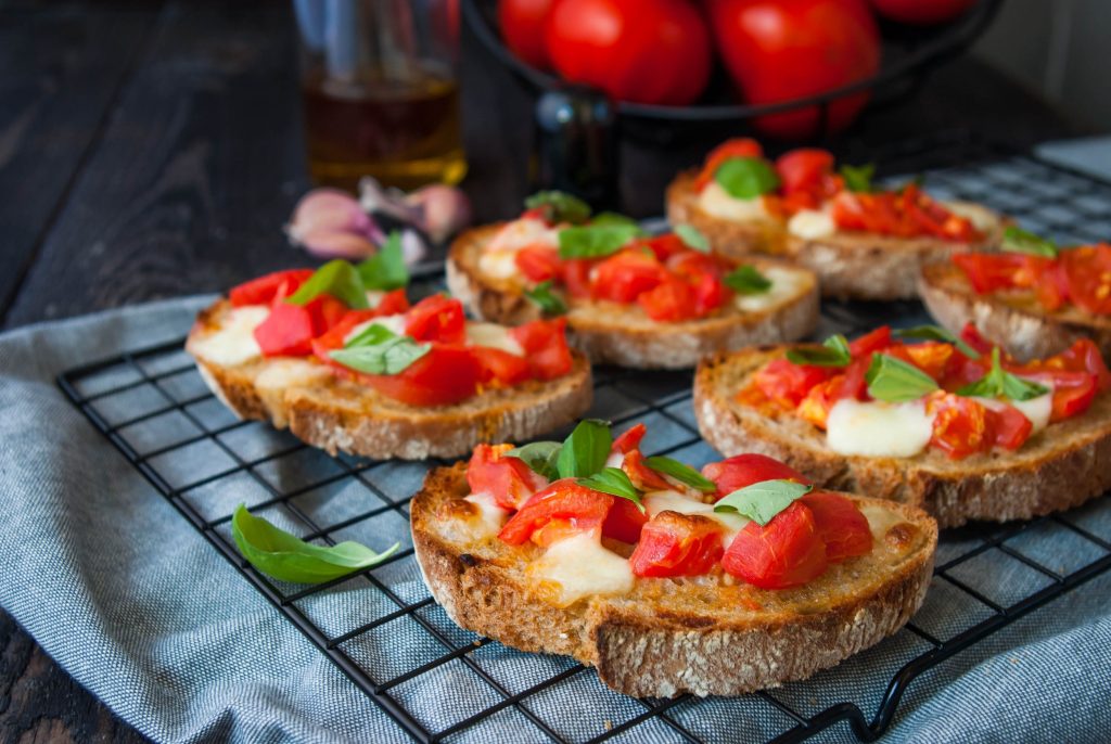 Bruschettas with tomatoes, mozzarella and fresh basil. Traditional Italian cuisine. Dark wooden background.